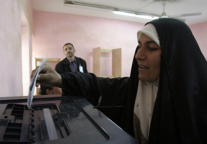 An Iraqi woman prepares to cast her voting ballot into one of the bins after filling it out at a polling site in Rawah, Iraq during the country’s first parliamentary election. (Photo: Shane S. Keller/2005)