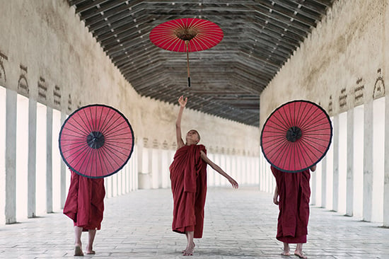 ICNL 2012-2013 Annual Report cover photo - A group of three monks with red umbrellas