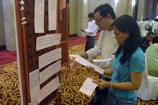 2016.07-Myanmar-ARL-Implementation-Workshop Participants reading over a poster at a July, 2016 workshop in Myanmar on the implementation of the Association Registration Law, convened by the CSO Working Group and the Ministry of Home Affairs, with the support of USAID and FHI 360.