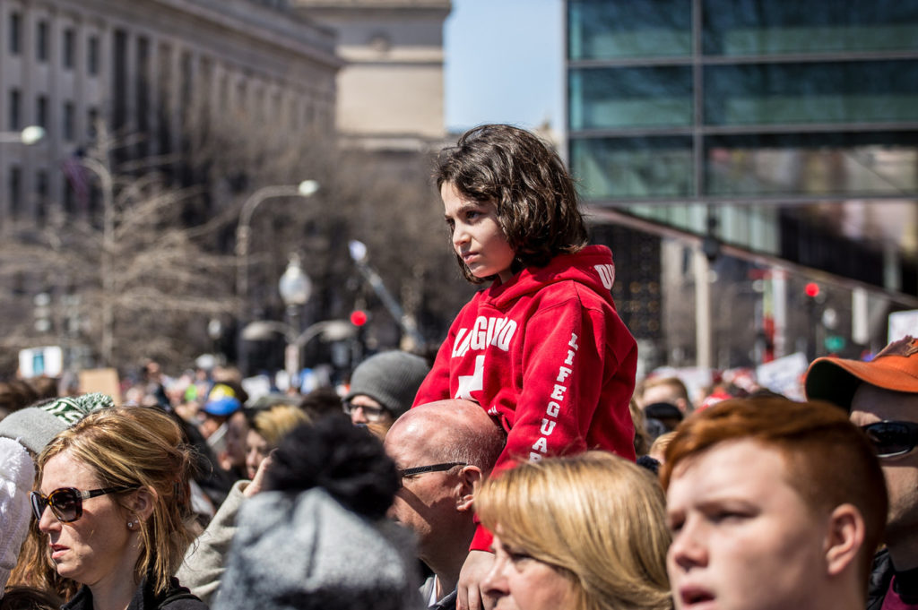 child on shoulders in crowd