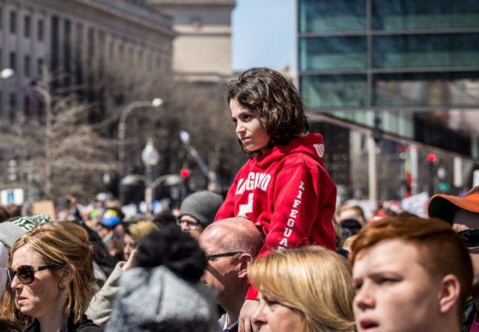 child on shoulders in crowd