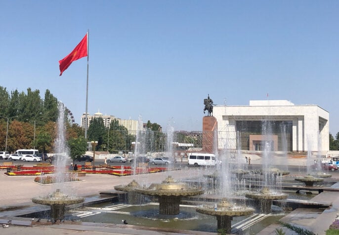 Ala Too Square Bishkek, the capital of the Kyrgyz Republic, on a very sunny, cloudless day. There are fountains and a large Kyrgyz flag on a tall flagpole billowing. (Photo: Emil Akhmatbekov)