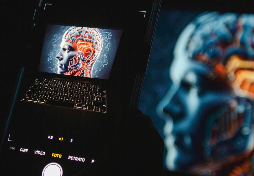Image of a phone screen depicting a robot and laptop keyboard