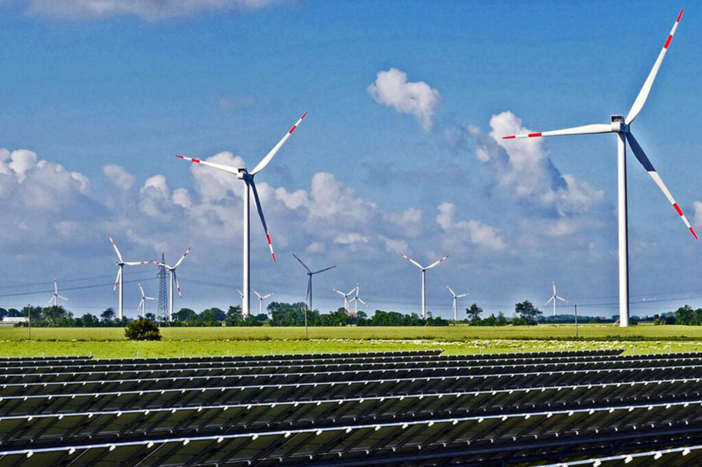 Solar panels, wind turbines, and an electricity pylon (Photo: hpgruesen/Creative Commons)