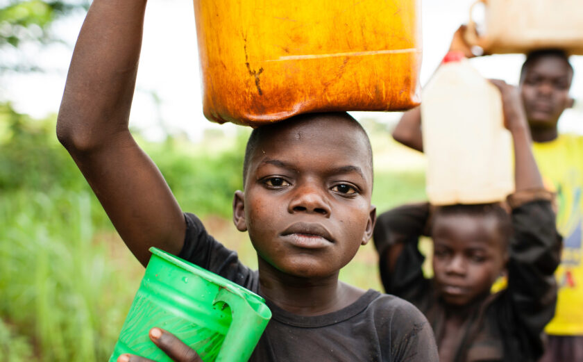 Donatien Voungoukpala, 13 (solid blue t-shirt), with his brothers Fleuri Rodrigue Hipai, 17, and Aime Bera-Mbolikia, 10, go to fetch water at a a nearby spring, their principle water source. August 20, 2012, Rounga Village, Bangassou, Central African Republic. Donatien and his family are IDPs who relocated to Bangassou from Rafai approximately one year ago as a result of the LRA conflict.