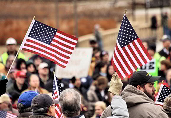US protest Workers hold US flags at a labor rally in Iowa (photo credit: Phil Roeder/Flickr)