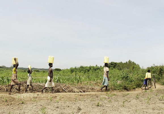 Four people walking with water buckets on head in drought stricken land (photo credit: pixabay.com)