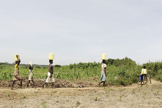 Four people walking with water buckets on head in drought stricken land (photo credit: pixabay.com)