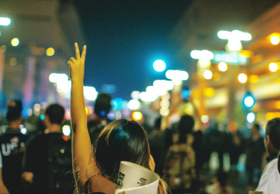 Women giving peace sign at protest (photo credit: unsplash.com)