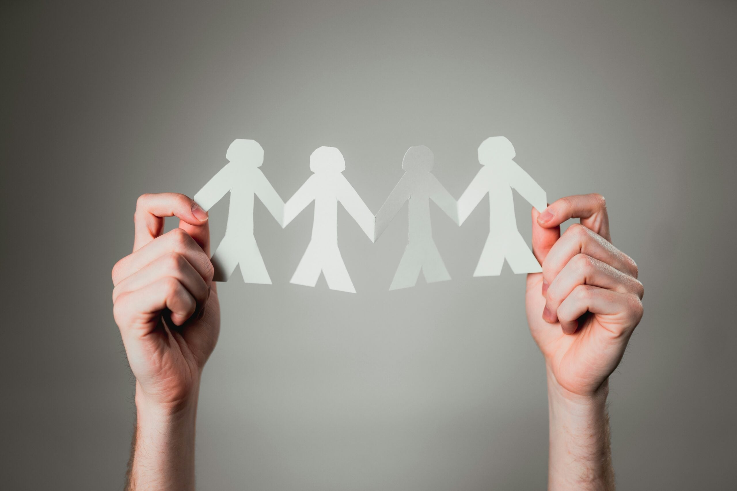 Cut out people held by human hands, photo by Andrew Moca via Unsplash