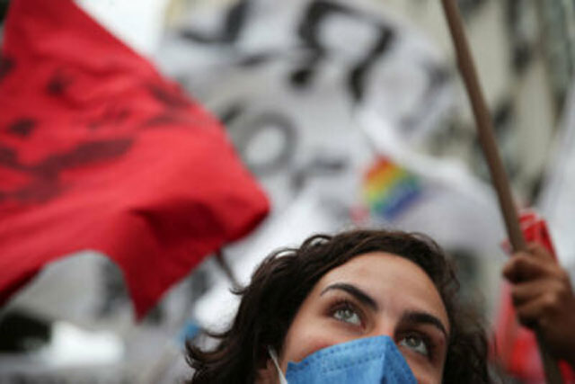 woman with mask on looking up with protest around