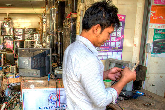 Man working in an electronic repair shop in Cambodia (Photo credit: Ethan Crowley)