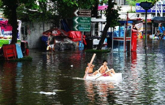 two boys on canoe in flood waters (photo credit: