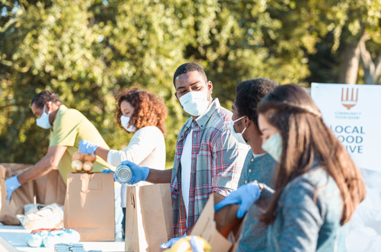 Group of people wearing masks, sorting food in bags for a food drive (Photo: istock)