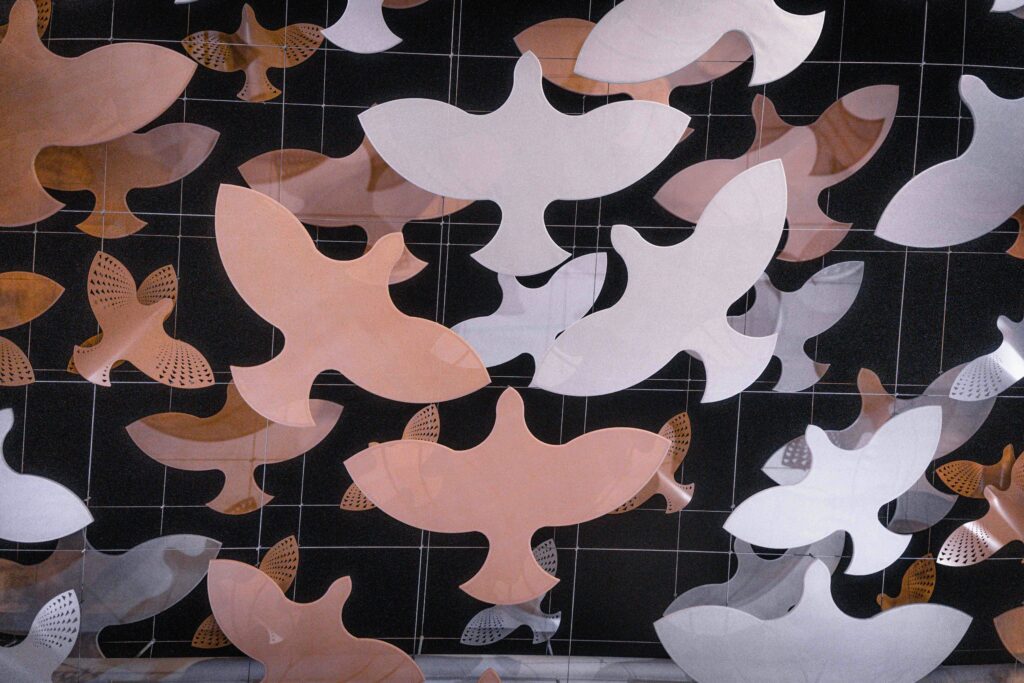 paper doves in white and peach appear to be hanged. Photo by ltadaki via unsplash
