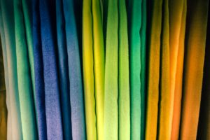 Photo of multi-color fabrics taken in Saida, Lebanon. The fabrics are draped vertically, and are teal, blue, yellow, green, orange, and yellow. (Photo: Jametlene Reskp/Flora Saltzmann/Unsplash)