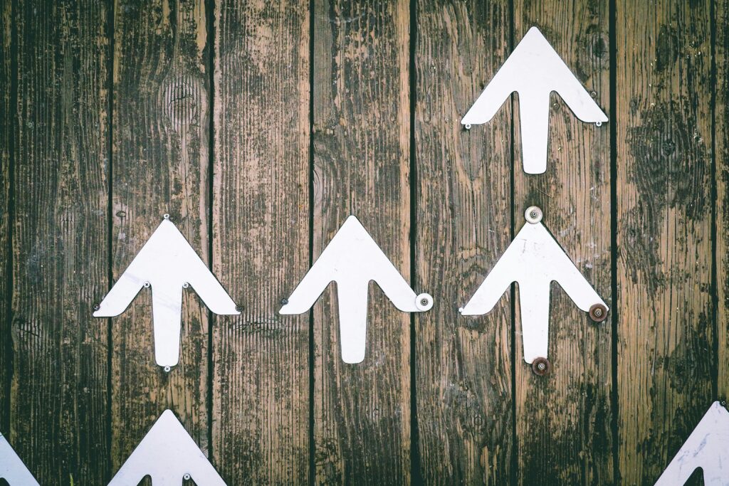 White arrows fixed on wood background. Photo by Jungwoo Hong via Unsplash