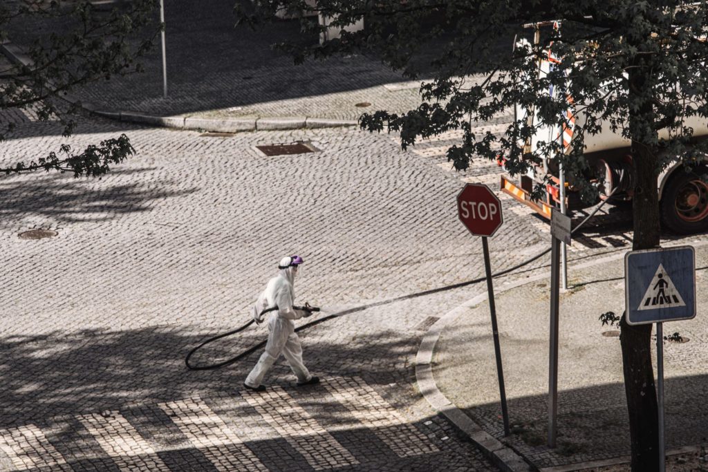 man in hazmat suit cleaning streets (photo credit: unsplash.com)