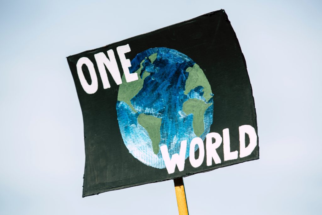 sign that says one world with Earth (photo credit: unsplash.com)