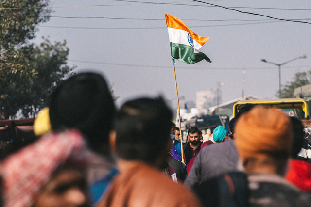 India’s FCRA; Farmers protesting holding India flag (photo credit: unsplash.com)