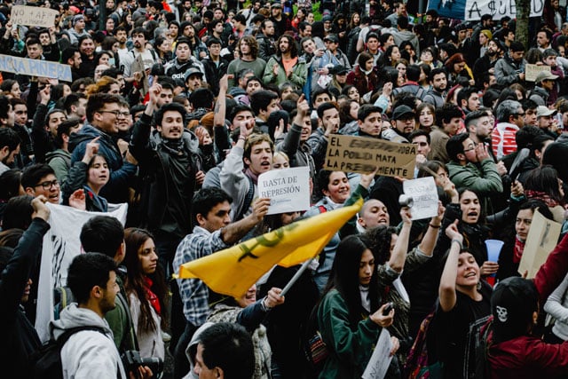 protestors in Chile with signs and flags (photo credit: unsplahs.com)