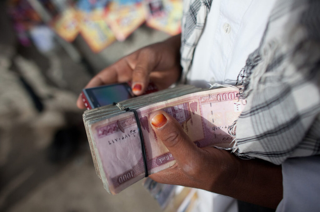 Person holding cash and a cell phone; FATF in the Middle East. (Photo: Jan Chipchase)