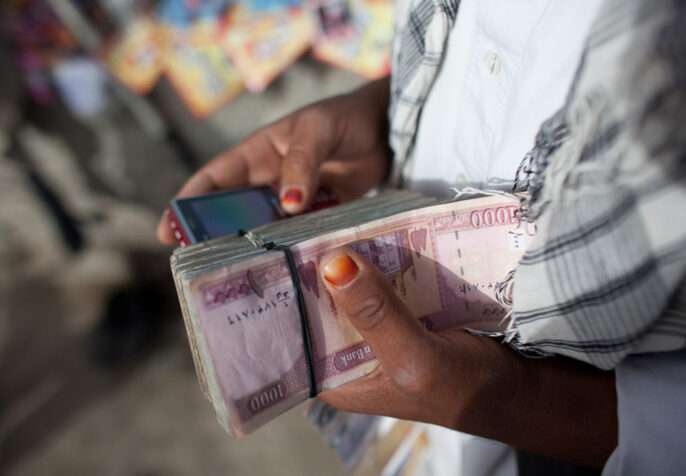 Person holding cash and a cell phone (Photo: Jan Chipchase)