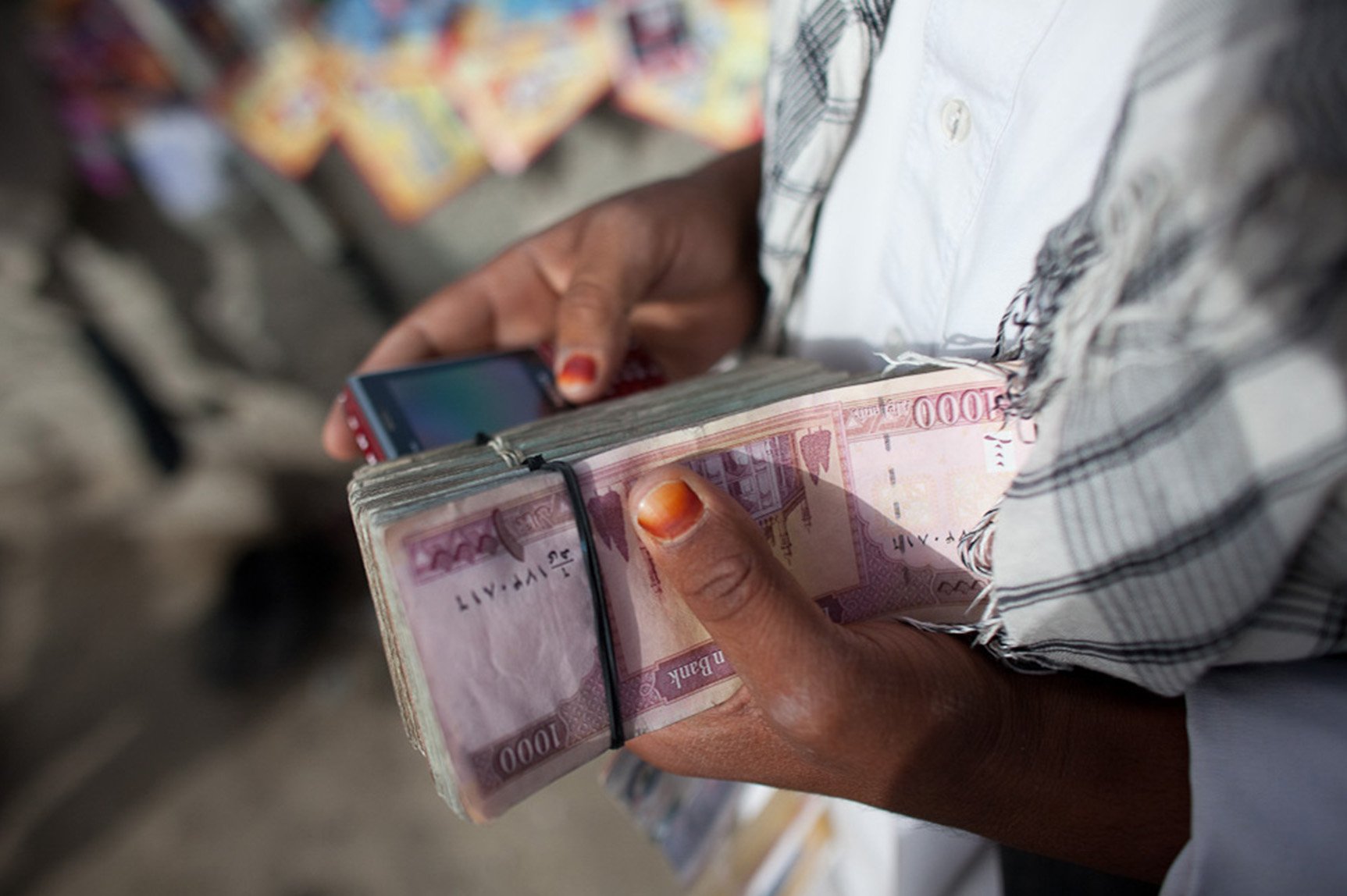 Person holding cash and a cell phone (Photo: Jan Chipchase)